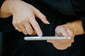 Close-up of woman using digital tablet with luxury accessories such as silver ring and pearl bracelet.