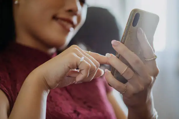 Fashionable business woman with luxury accessories such as golden ring, bracelet  while holding a smart phone at office