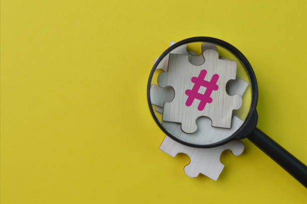 istock Magnifying glass and wooden jigsaw puzzle with HASHTAG symbol 1371257527