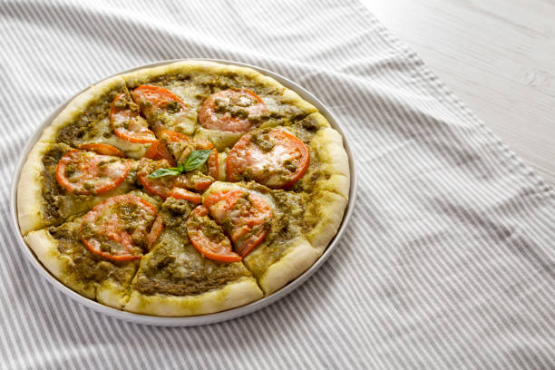 istock Homemade Pesto Pizza with Fresh Tomatoes and Mozzarella on cloth, side view. Copy space. 1371258324