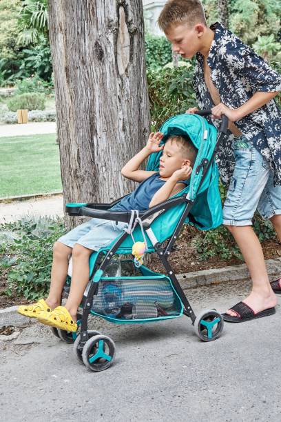 istock Boy pushes stroller with sitting younger brother in park 1371258355