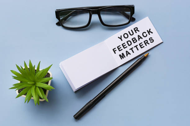 Text on notepad with reading glasses and potted plant on blue background Text on notepad with reading glasses and potted plant on blue background - Your Feedback Matters constructive feedback stock pictures, royalty-free photos & images