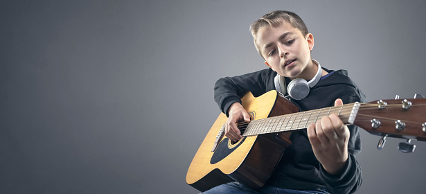 Teenager boy playing and learning the acoustic guitar background