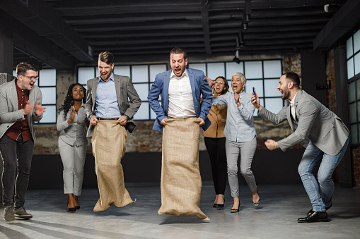 Large group of cheerful business colleagues having fun during a sack race at casual office.