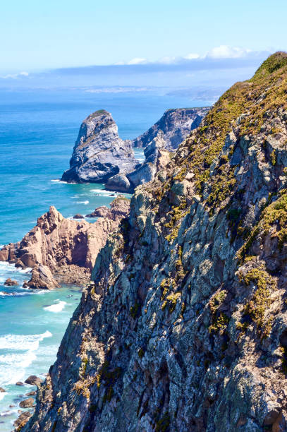 istock Vertical cliff and islet in the background over a blue sea. 1371261897