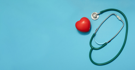 Stethoscope with red heart on blue background. Heart diseases. Doctors Day,  Healthcare and Medicine concept