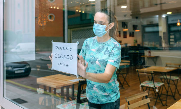 istock Woman placing coronavirus closure sign 1371269511