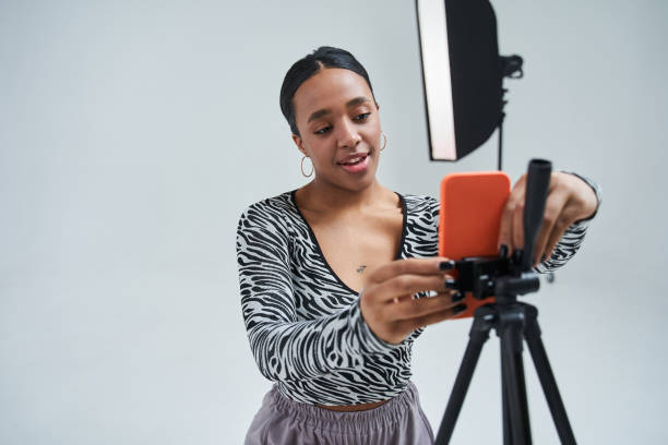 istock Delighted woman dancer putting smartphone at the tripod while preparing broadcasting 1371273747