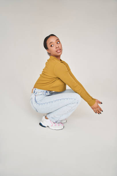 istock Multiracial woman looking away with serious face and kneeling while posing at the studio 1371273870