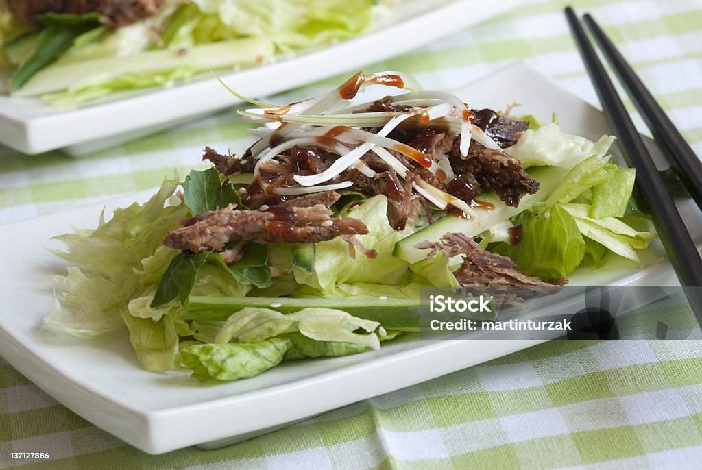 Crispy duck salad Crispy duck with iceberg lettuce, cucumber and hoisin sauce on a plate Chopsticks Stock Photo