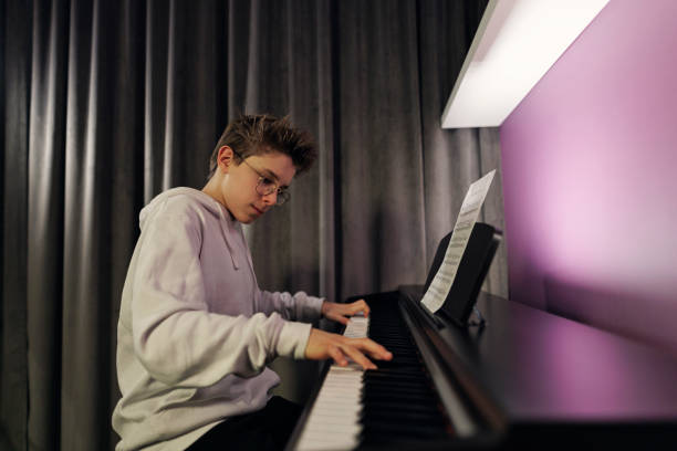 istock Teenage boy practicing piano at home 1371279865