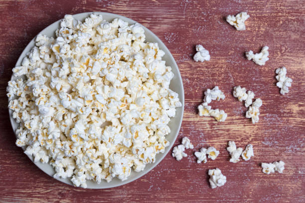 istock Popcorn in white ceramic bowl on red background. Top view, flat lay. Copy space 1371280913
