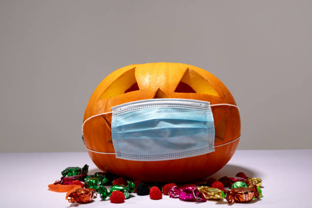 istock Halloween jack o lantern with face mask on grey background with sweets 1371281355