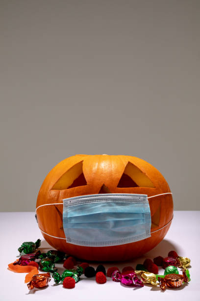 istock Halloween jack o lantern with face mask on grey background with sweets 1371282132