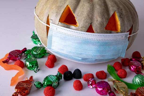 istock Halloween jack o lantern with face mask on grey background with sweets 1371283100