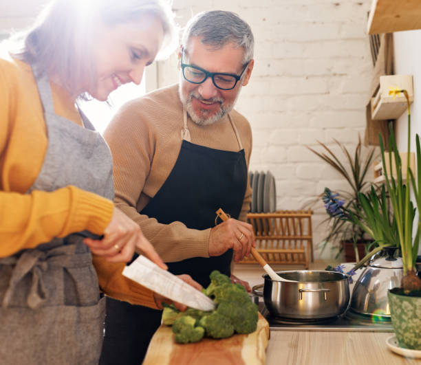 幸せな高齢の夫婦�は、居心地の良いキッチンで一緒においしいと健康的なランチを調理 - senior couple ストックフォトと画像