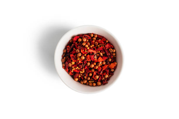 A creative spiral galaxy pattern made using turmeric powder, red chili flakes, and whole black pepper on a black background. The vibrant orange tones of turmeric combined with the contrasting textures of chili and pepper create a dynamic, cosmic visual effect. This abstract food art concept symbolizes Indian spices, creativity, culinary inspiration, and vibrant flavor. Perfect for themes related to cooking, ingredients, spice blends, food backgrounds, and artistic compositions.