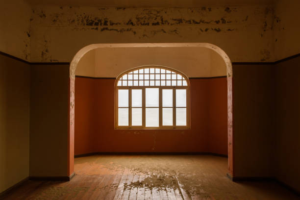 Room and arch window in Kolmanskop ghost town home Interior view of deserted house in Kolmanskop ghost town near Luderitz in Namibia, the site of an abandoned diamond mine abandoned place stock pictures, royalty-free photos & images