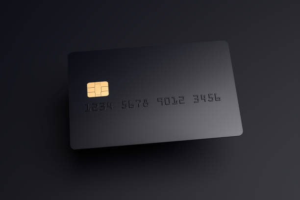 A blank black credit card hovering over a black surface with shadow stock photo