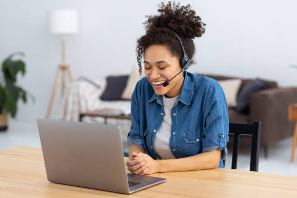 Portrait of happy African American female employee customer support services in headset sitting in modern office, online consultation. Woman call center. Female customer support or sales agent stock photo