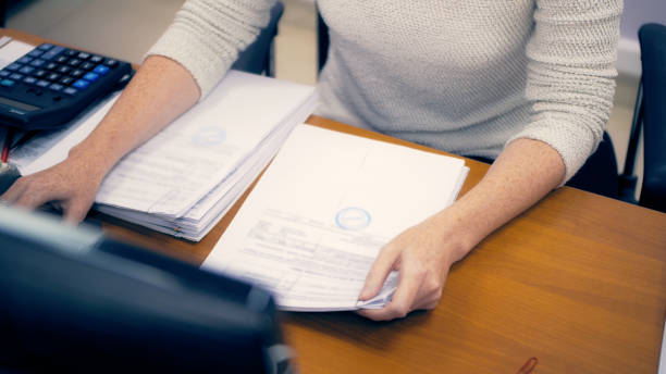 mujer en el cargo trabajando con documentos. informe trimestral - empleado de archivo fotografías e imágenes de stock