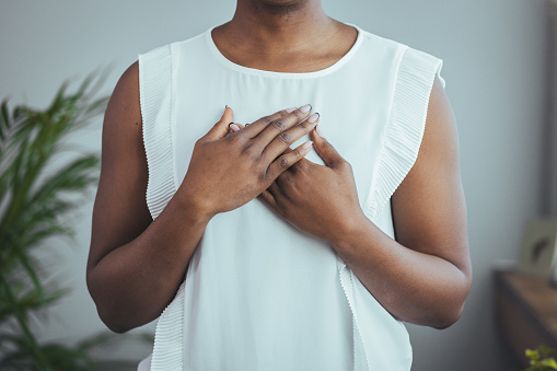 Cropped close up smiling grateful woman holding folded hands on chest, thankful young female expressing gratitude, thanking god and faith, feeling love, making wish, charity and support concept