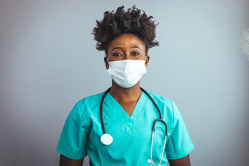 Portrait of an African American nurse wearing a protective face mask to avoid the transfer of germs during the COVID-19 outbreak. African american doctor wearing scrubs looking at camera smiling