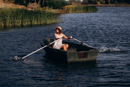 Perfect woman. Beautiful young woman in dress sitting in the rowboat . Adventure and vacation travel concept.