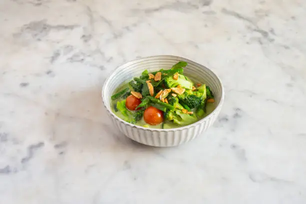 A bowl of vegetable curry on a marble table.