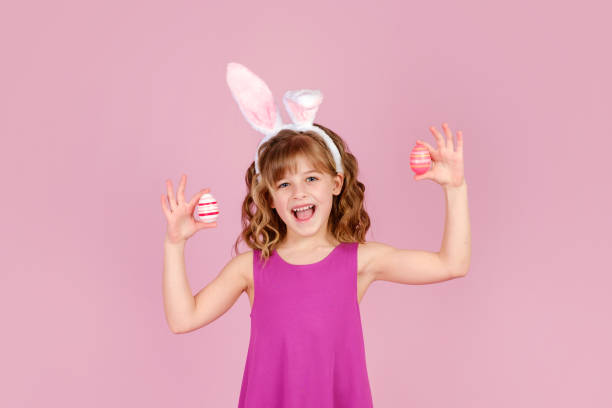 istock Little girl in Easter bunny ears smiling while holds in hands colorful eggs 1371301633