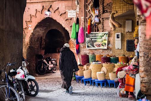 Marrakesh, Morocco - February 28, 2018: A typical street in the ancient Medina district of Marrakech. Photo contains local people doing various activities.