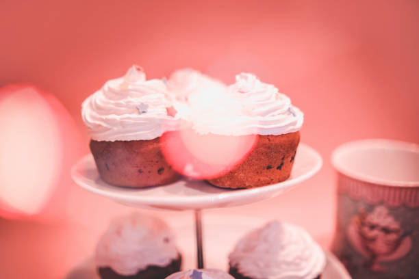 Cake stand with homemade muffins on pink background