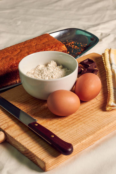 istock Homemade sponge cake on a white tablecloth with some ingredients: eggs, chocolate and flour. 1371303522