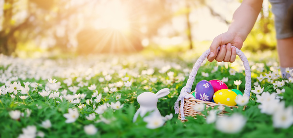 Child holding in his hand a basket with colourful eggs. Concept of celebrating of the Easter.