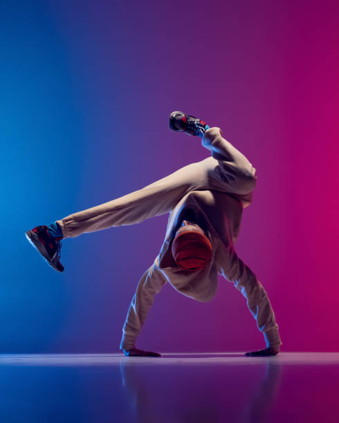 istock Studio shot of young flexible sportive man dancing breakdance in white outfit on gradient pink blue background. Concept of action, art, beauty, sport, youth 1371307971