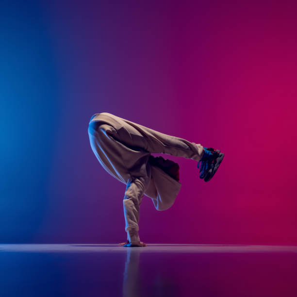 istock Studio shot of young flexible sportive man dancing breakdance in white outfit on gradient pink blue background. Concept of action, art, beauty, sport, youth 1371307979