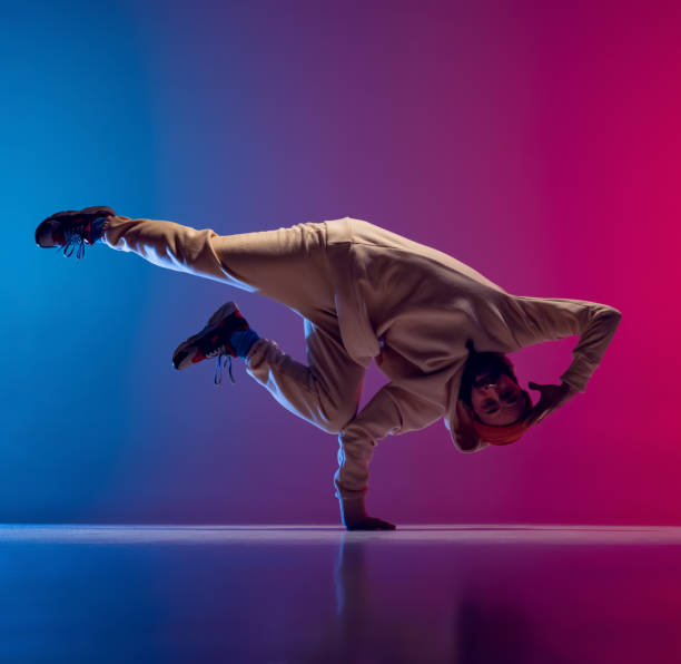 istock Studio shot of young flexible sportive man dancing breakdance in white outfit on gradient pink blue background. Concept of action, art, beauty, sport, youth 1371307981
