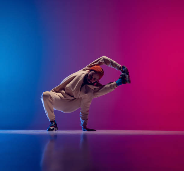 istock Studio shot of young flexible sportive man dancing breakdance in white outfit on gradient pink blue background. Concept of action, art, beauty, sport, youth 1371307988