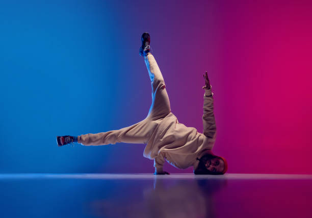 istock Studio shot of young flexible sportive man dancing breakdance in white outfit on gradient pink blue background. Concept of action, art, beauty, sport, youth 1371307989