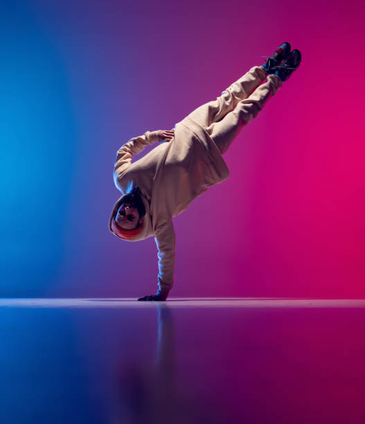 istock Studio shot of young flexible sportive man dancing breakdance in white outfit on gradient pink blue background. Concept of action, art, beauty, sport, youth 1371307995