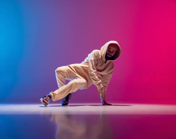 istock Studio shot of young flexible sportive man dancing breakdance in white outfit on gradient pink blue background. Concept of action, art, beauty, sport, youth 1371308006