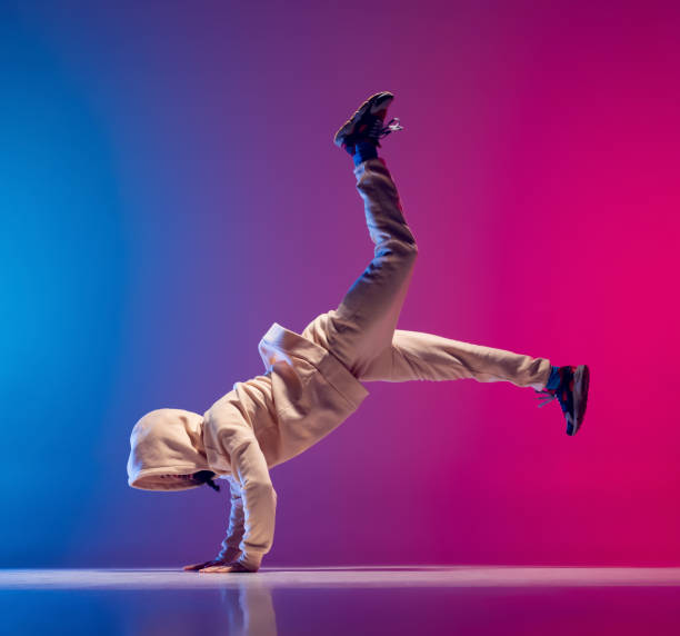 istock Studio shot of young flexible sportive man dancing breakdance in white outfit on gradient pink blue background. Concept of action, art, beauty, sport, youth 1371308009