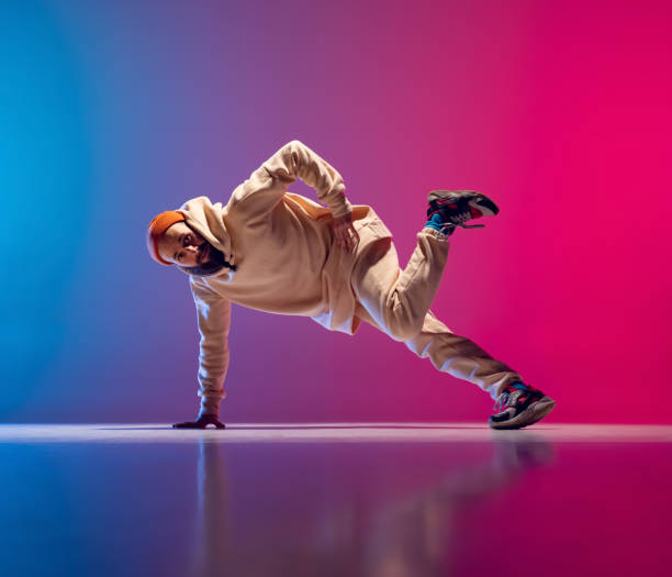istock Studio shot of young flexible sportive man dancing breakdance in white outfit on gradient pink blue background. Concept of action, art, beauty, sport, youth 1371308011