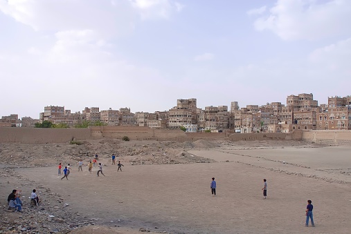 Cityscape of Sanaa , Yemen and the kids playing football in the vast playground
