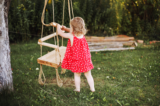 girl in the garden playing with swings. baby playing in the garden alonegirl in the garden playing with swings. baby playing in the garden