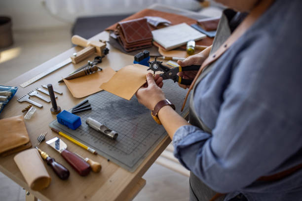 istock Female leather craftsman making custom made leather wallet in her workshop 1371310470