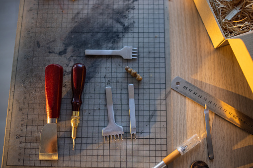 Leather crafting tools on wooden table in workshop