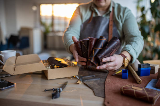 istock Woman holding box with handmade leather wallets in her leather craftsman workshop 1371312198