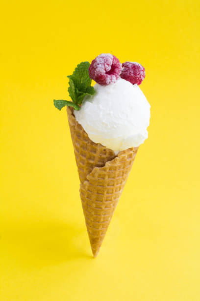 crème glacée à la vanille dans un cône de gaufre avec framboise sur fond jaune. gros plan. - raspberry ice cream close up fruit mint photos et images de collection