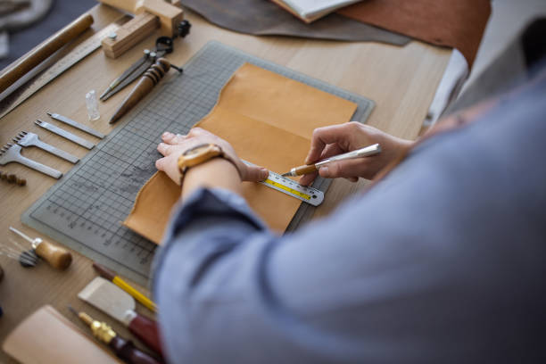 istock Female leather craftsman making custom made leather wallet in her workshop 1371313554